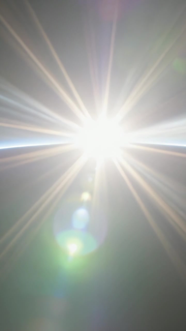 Vertical video: Emitting central starburst rays and shifting lens flares over limb, lens artifacts