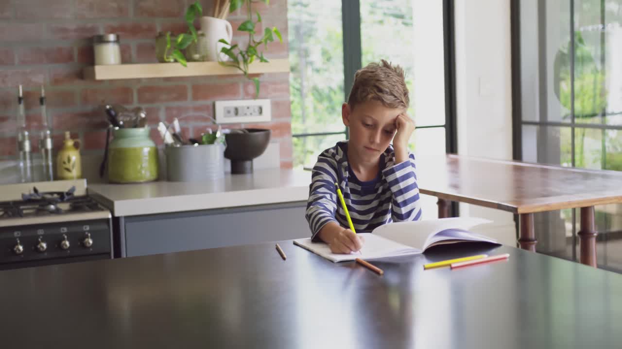 Boy studying at table in kitchen at home 4k