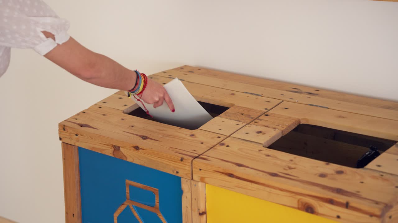 A woman throws paper over paper and cardboard collection bins at the office