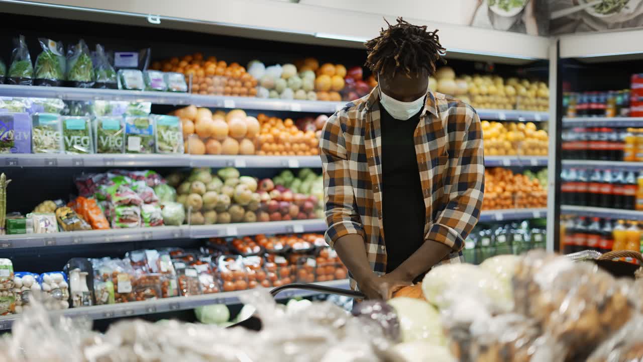 Man in mask push cart, choosing products in the fresh produce section