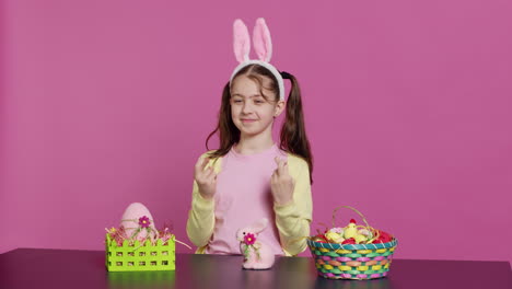 small cheerful kid posing with fingers crossed in studio