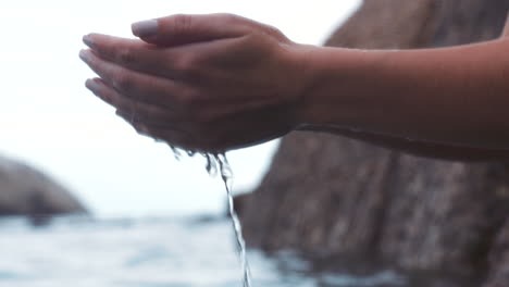 Hand,-water-and-nature-with-a-woman-by-the-beach