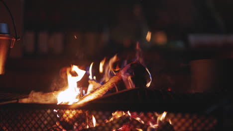 fiery smoking log burning over swedish homestead barbecue close up in darkness