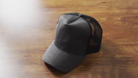 Video-of-close-up-of-gray-baseball-cap-lying-on-wooden-table