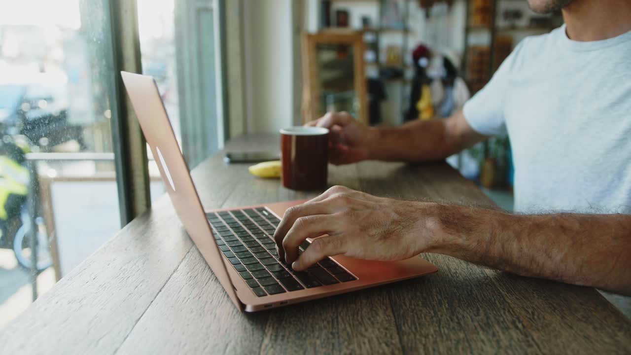 hombre trabajando en una computadora portátil en un café