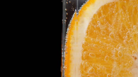 una rodaja de naranja bajo el agua con burbujas de aire.
