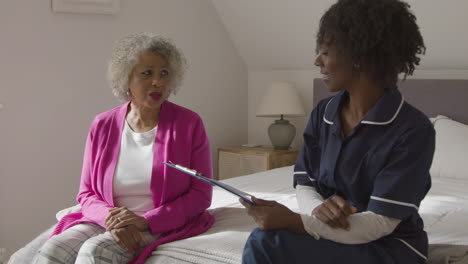 middle aged nurse conducting a home visit with senior woman