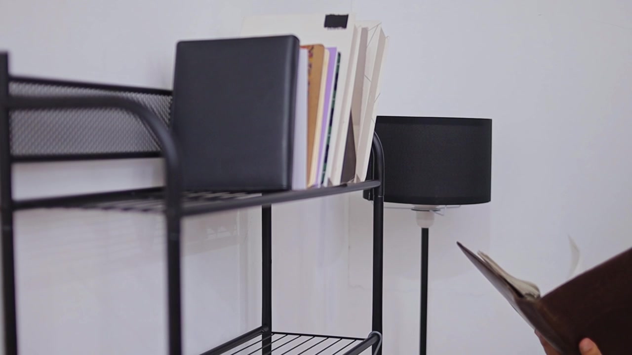 Close-up of hands student taking notebook from metal bookshelf in minimalist room