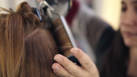 The-Hairdresser-Continues-Curling-Hair-To-A-Beautiful-Long-Haired-Girl-With-A-Ploy