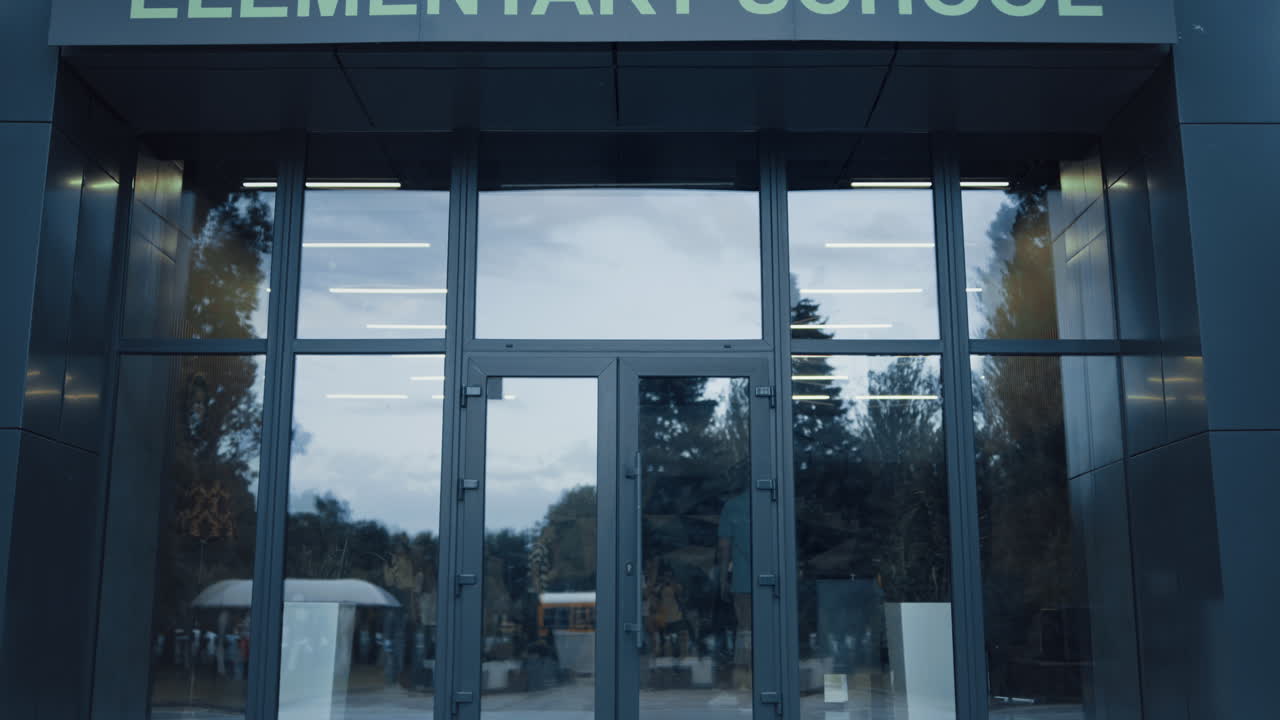 начальная школа снаружи с закрытой дверью. окно отражает небесные деревья