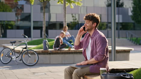 joyful guy answering call in urban park closeup. cheerful freelancer speaking