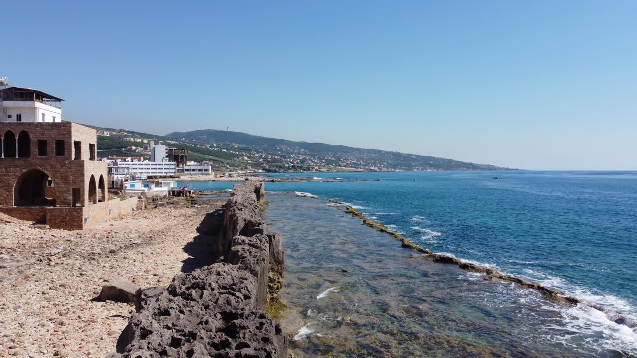 Phoenician sea wall at Batroun: Coastal city with hill range - Drone flying shot