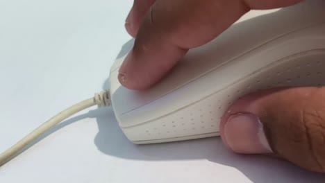la mano del hombre está haciendo clic y desplazando el ratón blanco de la computadora