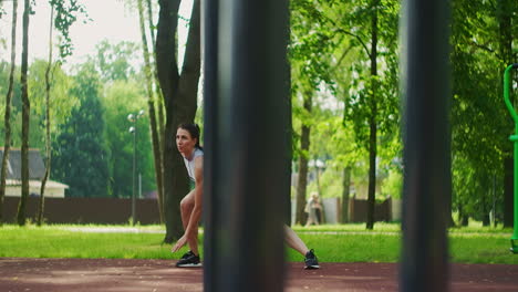 atleta femenina realiza estocadas laterales trabajar sus piernas y saltar en el parque en cámara lenta. mujer hermosa jugando deportes en el parque.