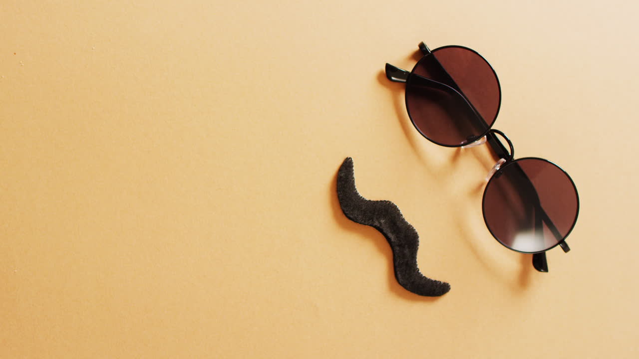 Video of false moustache and round sunglasses on yellow background with copy space