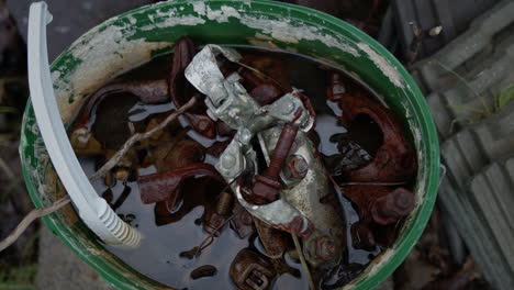 cubo de tornillos metálicos oxidados y plástico en agua