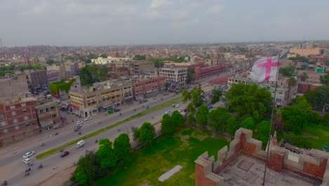 Aerial-flight-over-the-Church,-Crossing-the-Flag-and-Minarets-of-the-Church,-A-view-of-city-and-a-busy-road-with-metro-bus-station-and-fly-over