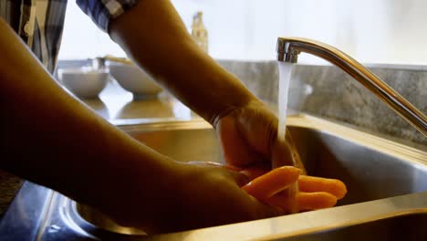 senior man washing root vegetable in kitchen 4k