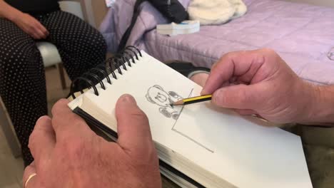 un hombre dibuja un oso de peluche en un cuaderno de bocetos