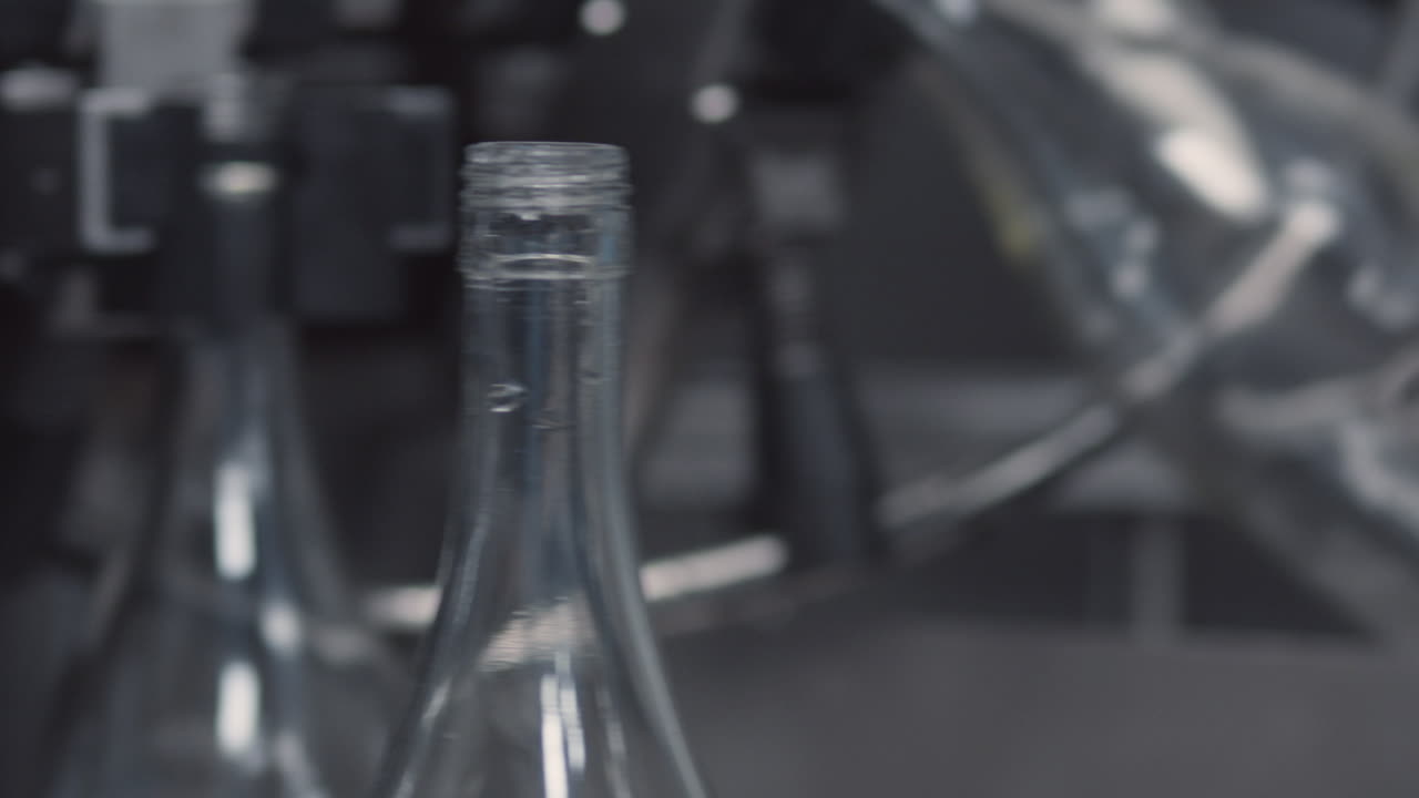 Medium shot of an industrial production line with glass bottles in a row, ready for the filling process.