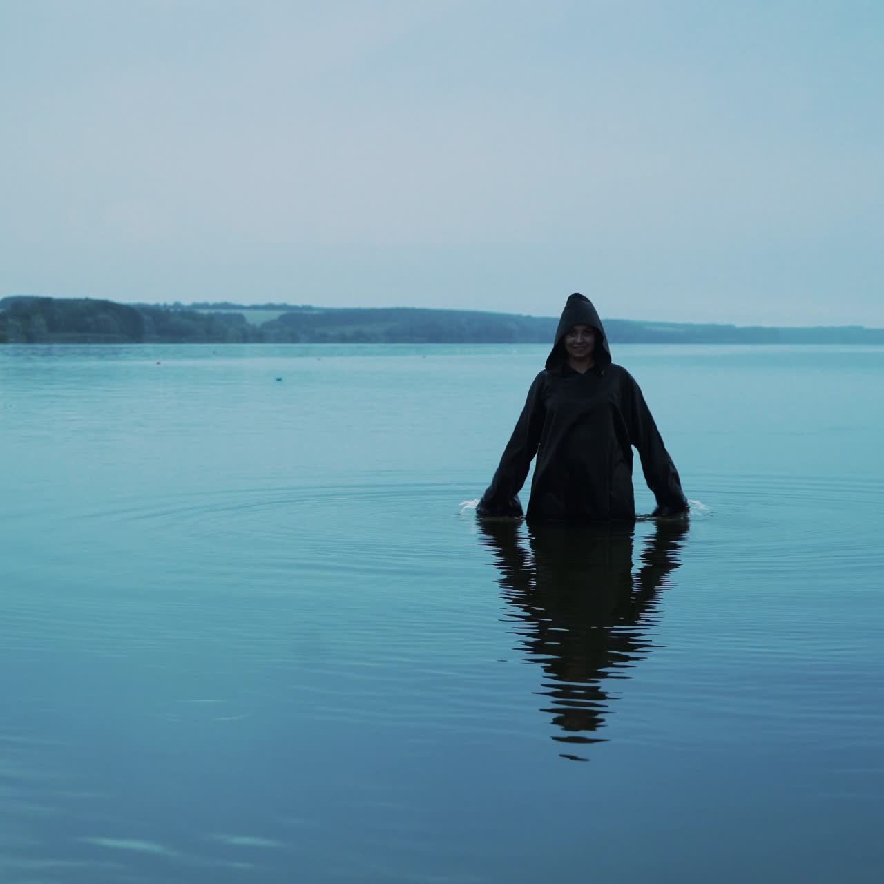 Female figure in black mantle in the river. Divination by the water
