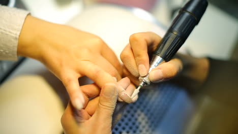 closeup shot of a woman in a nail salon receiving manicure by beautician
