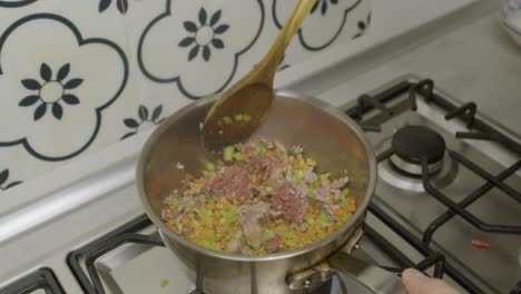 stirring minced meat and vegetables inside hot cooking pot