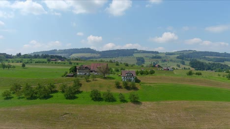 Paso-Elevado-De-Kussnacht:-Moviéndose-Sobre-Un-Pintoresco-Valle-De-Agua-Y-Un-Pueblo-En-Las-Montañas-De-Los-Alpes,-Suiza,-Europa,-Drone-|-Dramático-Reverso-Cinematográfico-De-Una-Pequeña-Casa-En-Un-Vasto-Campo.