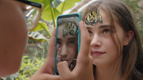 hermosa mariposa en la cara de las niñas con un amigo feliz tomando fotos usando un teléfono inteligente amigos divirtiéndose en el zoológico santuario de vida silvestre compartiendo excursiones en la naturaleza en las redes sociales imágenes 4k