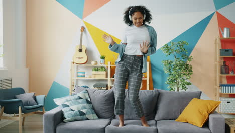 woman dancing on a sofa with headphones