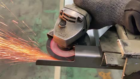 hands using a grinding machine to grind iron