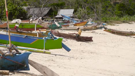 fisherman sitting among indonesian outriggers