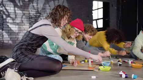 jóvenes activistas ambientales pintando carteles sentados en el suelo