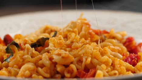 sticking a silver fork into fusilli pasta with tomato sauce, lifting it up and stretching melted mozarella cheese, mouthwatering shot on motorized slider from left to right