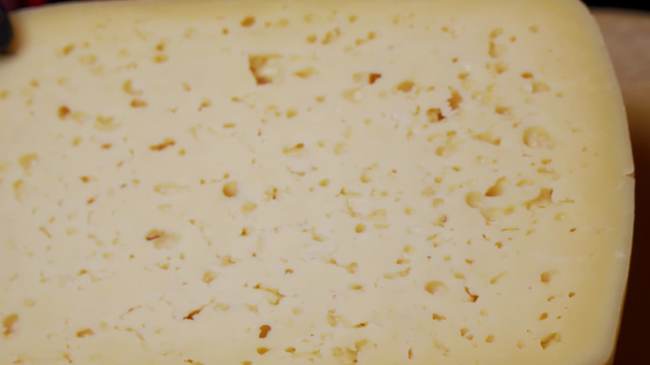 단단한 치즈의 큰 조각 - 특징적인 구이있는 치즈 표면의 질감.