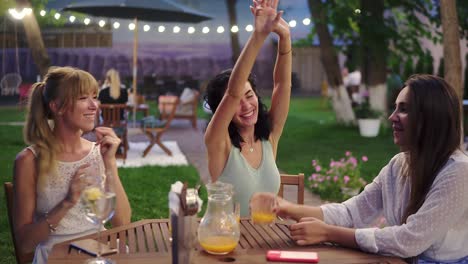 happy, three attractive women having fun and dancing in the restaurant outdoors in the evening dusk