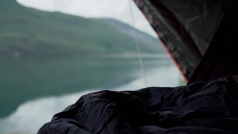 person sleeping inside tent near mountain lake. handheld