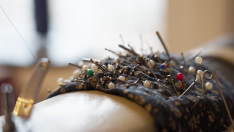 close-up of a pin cushion filled with sewing pins and needles in a workshop setting