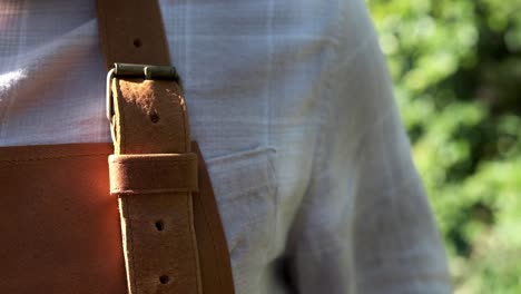 man puts on a leather apron and tightens the straps