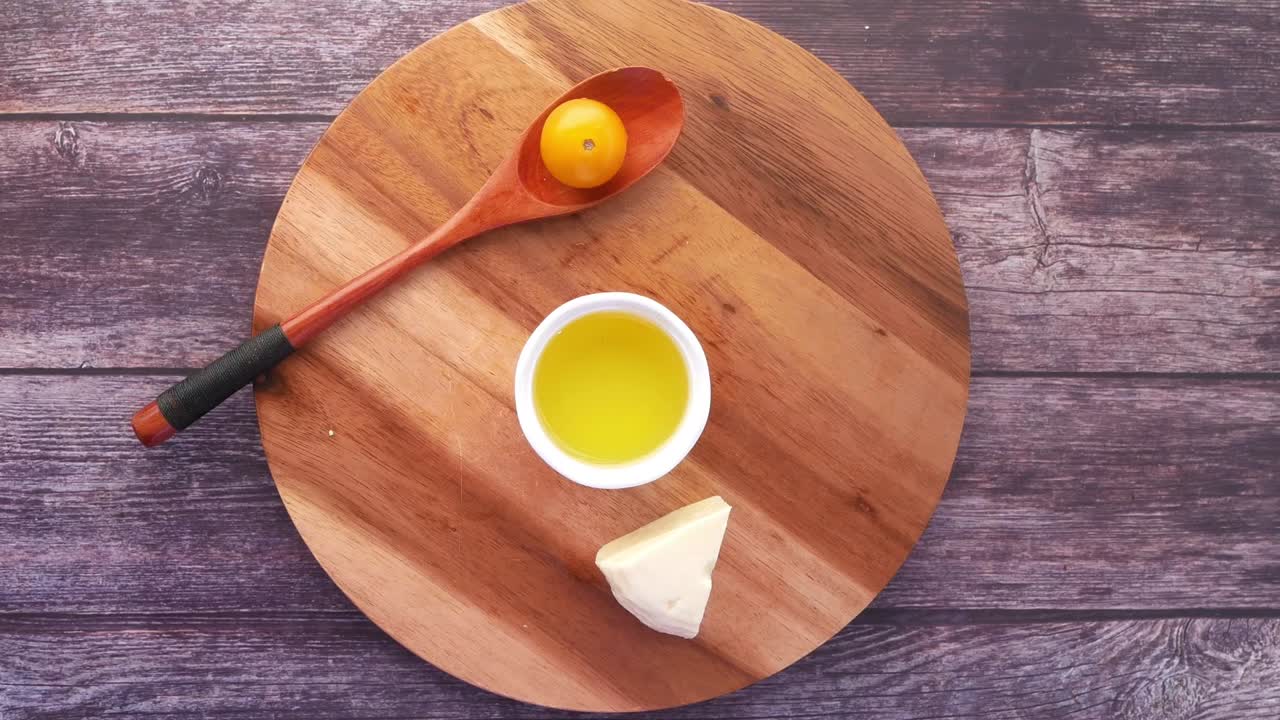 queso, aceite de oliva y tomate en una tabla de madera