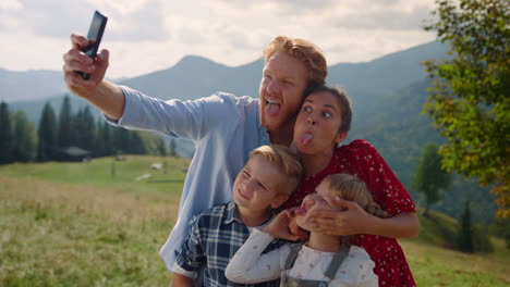 playful family grimacing selfie on smartphone standing mountain slope close up.