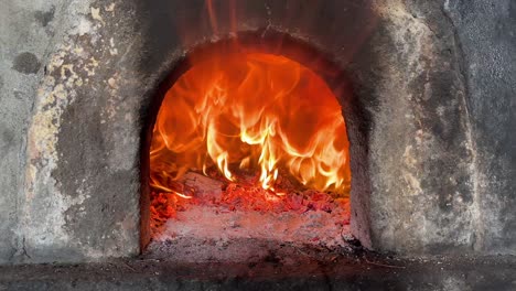 stone oven with logs on fire, flames getting out of the oven