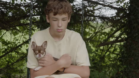 teenager on a swing holding a small dog