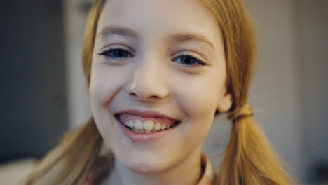 Portrait-shot-of-the-cute-blonde-teen-girl-with-two-tails-smiling-cheerfully-in-the-camera.-Close-up.-Inside