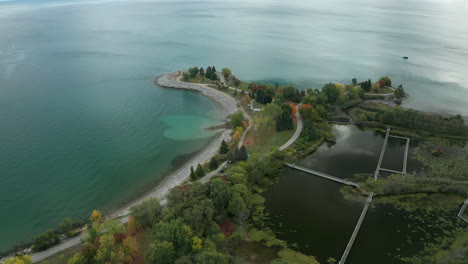 Drone-shot-flying-over-land-towards-clear-blue-water,-passing-a-small-heart-shaped-area