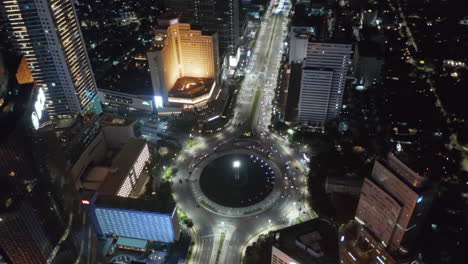 Vista-Aérea-Nocturna-De-Drones-Acercándose-A-La-Rotonda-Del-Monumento-Selamat-Datang-Con-Tráfico-Rápido-De-Automóviles-En-Yakarta,-Indonesia