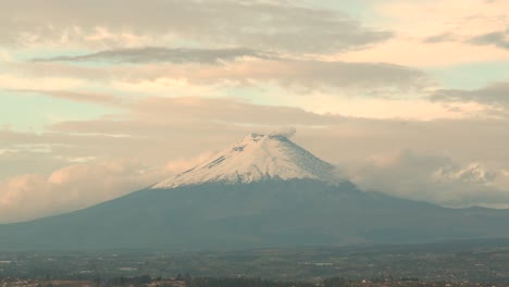 Malerischer-Blick-Auf-Den-Vulkan-Cotopaxi-Mit-Einer-Rauchwolke,-Die-Von-Seinem-Gipfel-In-Ecuador-Aus-Einer-Entfernten-Aufnahme-Des-Berges-Mit-Bewölktem-Himmel-über-Ihm-Treibt