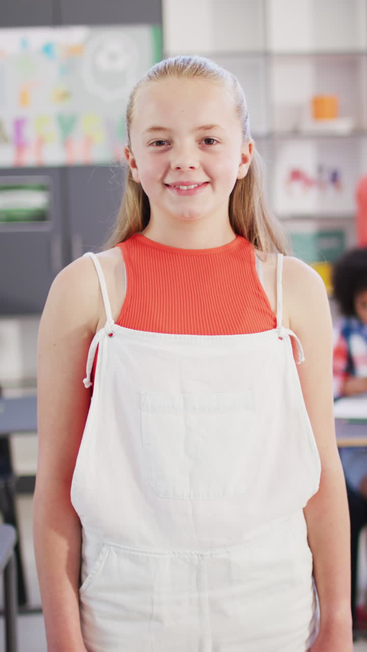 Vertical video of portrait of happy caucasian schoolgirl in school