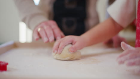 daddy teaches boy how to knead and shape bread dough in the kitchen