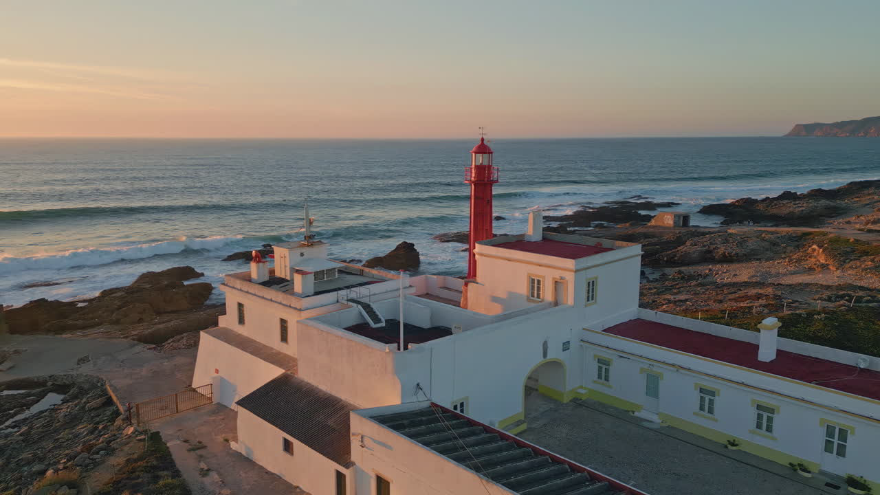 Panoramic sunset seascape lighthouse standing rocky seashore aerial view.